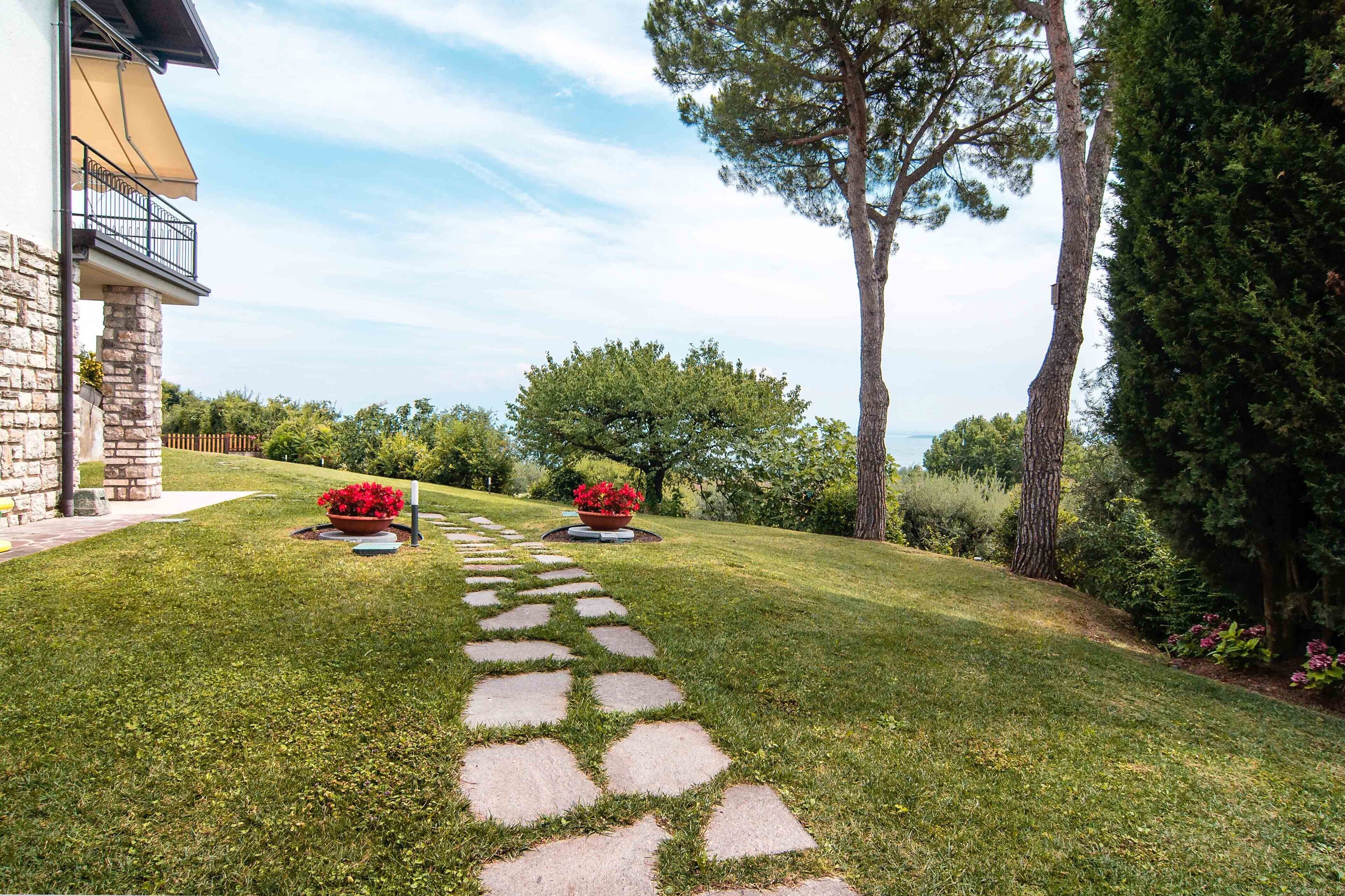 A stone pathway leading to a house with a balcony.