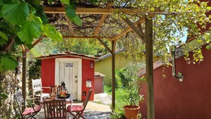 A covered patio area with a wooden pergola, a small BBQ zone, and a table with chairs. - Historic house lovingly furnished in original vintage style (Cesio)