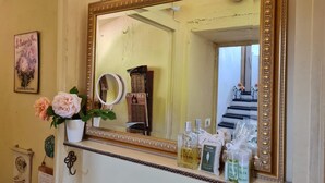 A bathroom with a large ornate mirror, a vanity with toiletries, and a floral arrangement. - Historic house lovingly furnished in original vintage style (Cesio)
