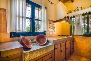 Une cuisine avec un mur recouvert de carreaux, une cuisinière et une fenêtre avec des rideaux.