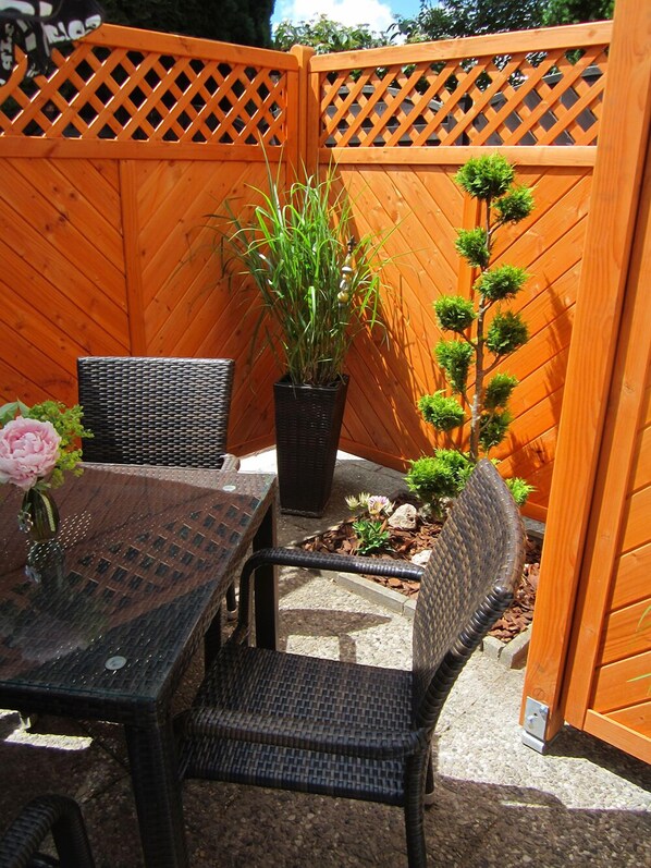 An outdoor patio with wicker furniture, a potted plant, and a small tree. - New apartment in unique dragon house in Duderstadt / Old Town (Duderstadt)