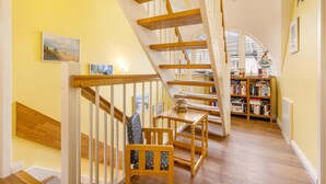 Un escalier avec des rampes en bois et une bibliothèque en arrière-plan.