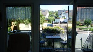 Ett rum med utsikt över en balkong, en stol, ett bord och ett tangentbord.