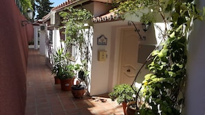 A narrow alleyway with potted plants, a door labeled "Casa de Ensueno", and a utility box.