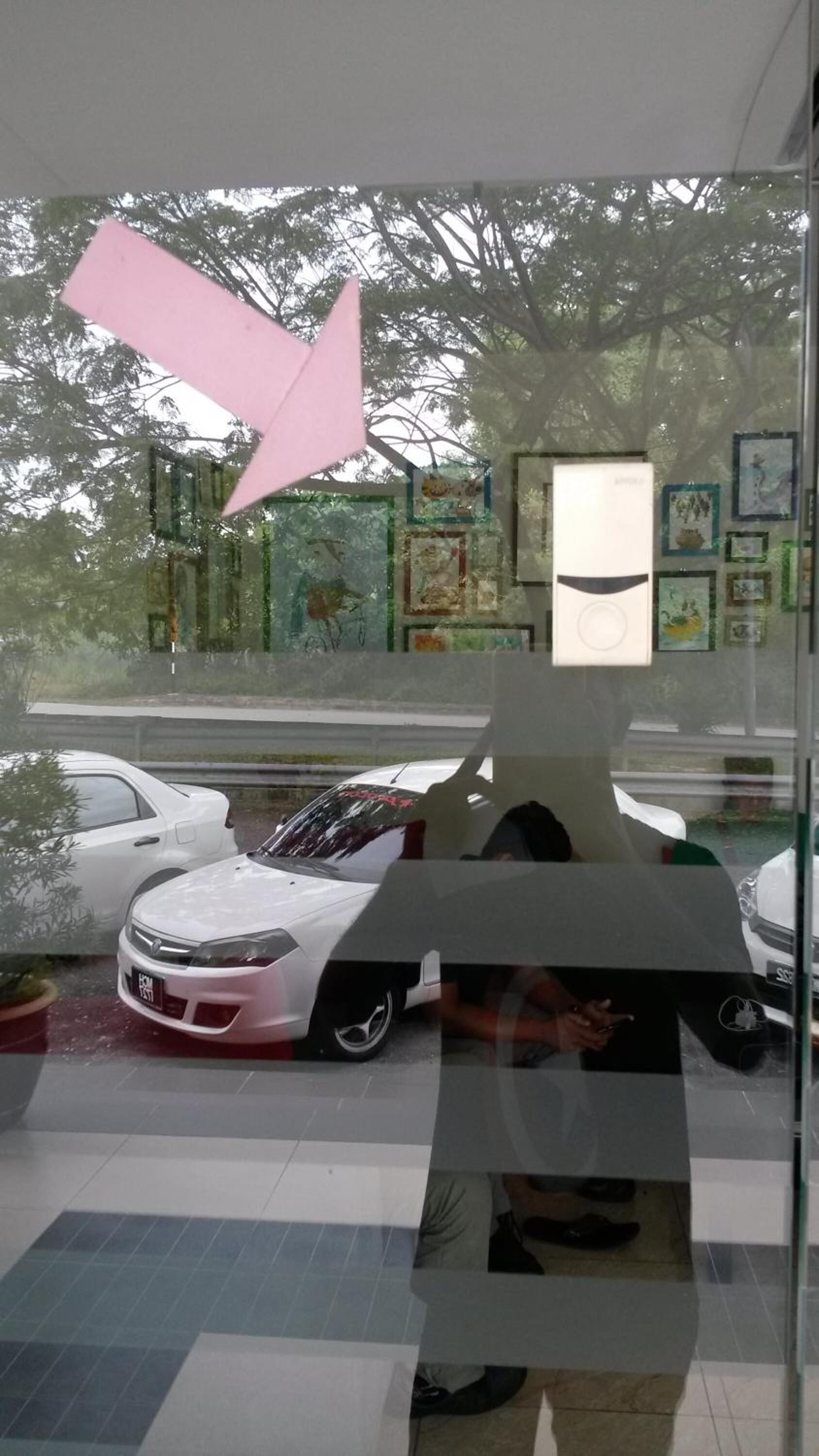 A modern interior with a glass wall, a white car model, and a large pink arrow decoration.