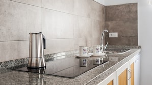 Eine Küche mit einem Edelstahl-Wasserkocher, zwei weißen Tassen mit blauen Verzierungen, einer Granitarbeitsplatte und einem Edelstahl-Armaturen.