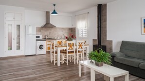 Eine moderne Küche mit Essbereich, einer Waschmaschine und einem grauen Sofa.
