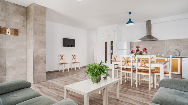 Ein modernes Wohnzimmer mit Essbereich, einer Küche und einem an der Wand befestigten Fernseher.