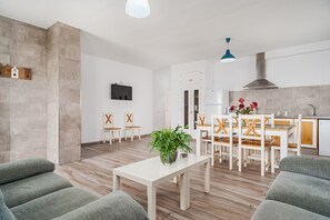 En moderne stue med spiseområde, køkken og et TV ophængt på væggen.