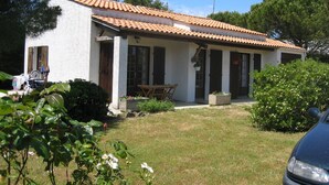 Une maison de plain-pied avec un toit en tuiles, un porche à l’avant et un petit jardin.