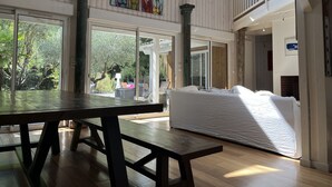Een ruime kamer met grote ramen, een houten tafel en een bed.