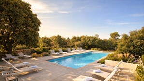 Una piscina rectangular con sillones de descanso y una pared de piedra.