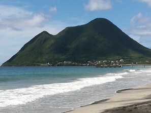 A beach with a mountain in the background and a small settlement visible on the shore.