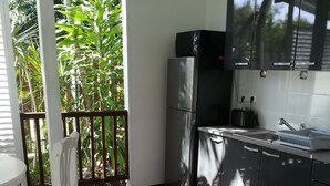 A kitchen with a refrigerator, a sink, and a dining area with chairs. - bungalow the box lace (Le diamant)