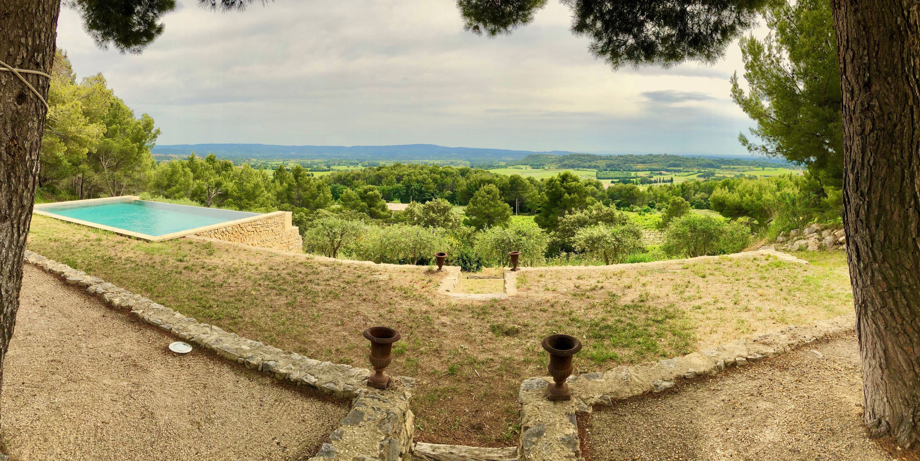 A pool with a view of a green landscape and distant hills.