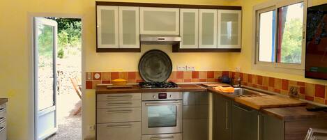 A compact kitchen with stainless steel appliances, a window with a view, and a tiled backsplash.