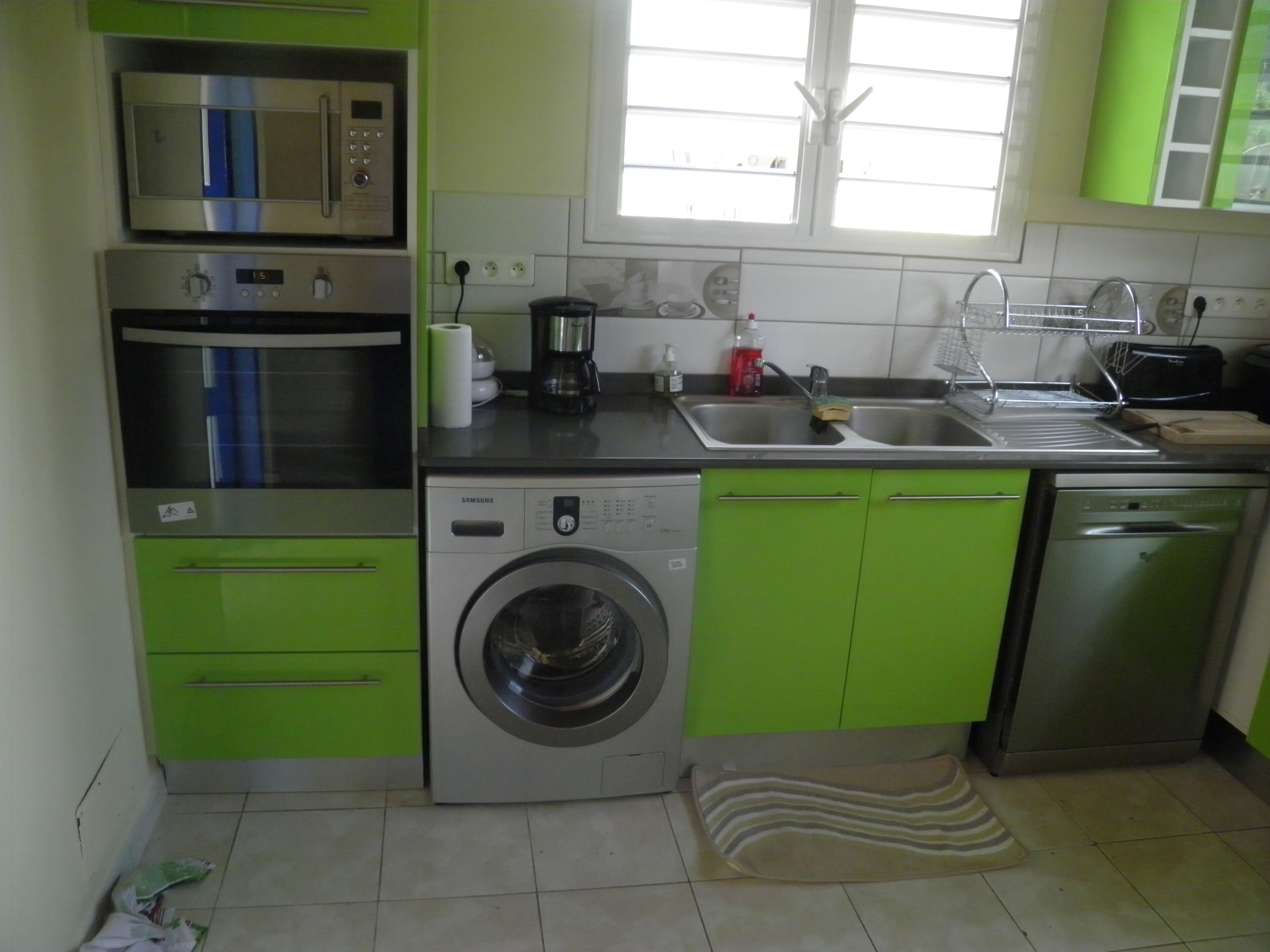 A compact kitchen with a microwave, oven, washing machine, and dishwasher.