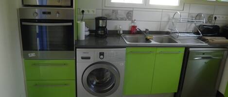 A compact kitchen with a microwave, oven, washing machine, and dishwasher.