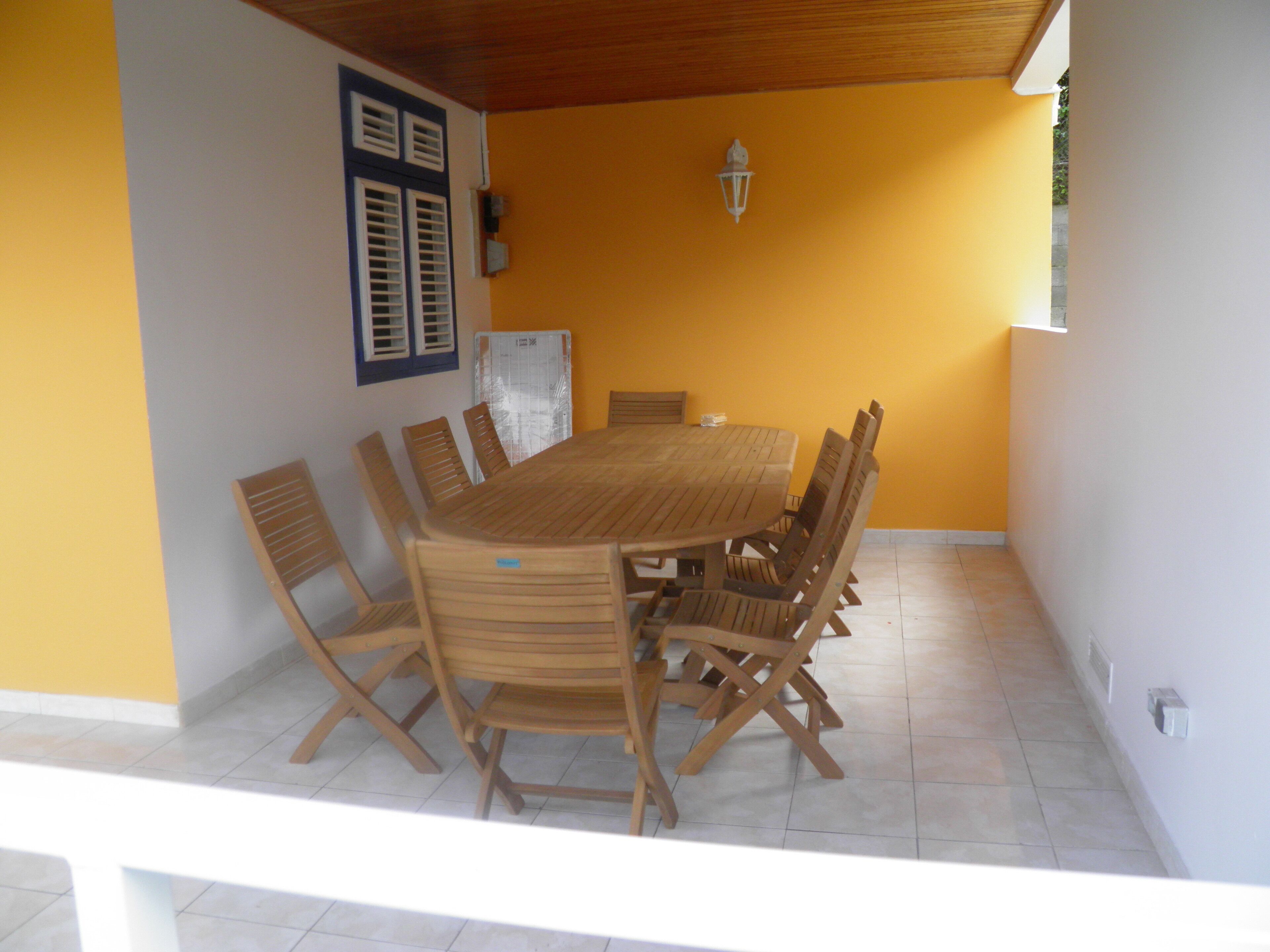 Un espace repas avec une grande table et des chaises en bois, un plafond blanc et un mur jaune.