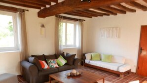A living room with a sofa, a coffee table, and a wooden ceiling.