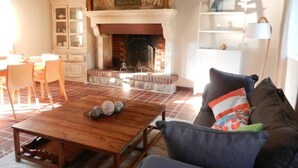 A cozy living room with a fireplace, wooden furniture, and a tiled floor.