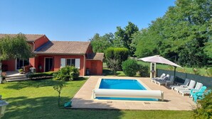 Una casa amb piscina, un patí amb gandules i un jardí ben cuidat.