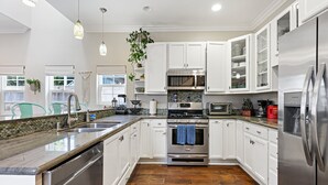 Una cocina moderna con armarios blancos, electrodomésticos de acero inoxidable y piso de madera.