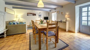 A dining area with a wooden table and chairs, a sofa, a TV, and a lamp. - House on the beach for 6 people in Crozon (Crozon)