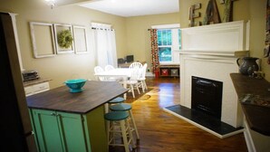 A kitchen with a wooden island, a dining area with white chairs, and a fireplace. - Spacious North Shore Bungalow @ Coolidge Park (Chattanooga)