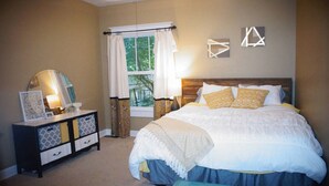 A bedroom with a bed, bedside table, dresser, and a window with curtains. - Spacious North Shore Bungalow @ Coolidge Park (Chattanooga)