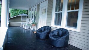 A covered porch with two black bean bags, white rocking chairs, and a potted plant. - Spacious North Shore Bungalow @ Coolidge Park (Chattanooga)