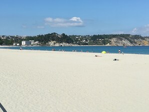 Ein weiter Sandstrand mit blauem Himmel und ruhiger See.