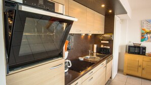 Een moderne keuken met een inbouwoven, een roestvrijstalen spoelbak en houten kastjes.