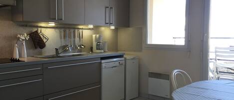 A compact kitchen with a dishwasher, a coffee maker, and a window providing natural light.