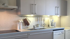 Una cocina moderna con gabinetes grises, un lavamanos de acero inoxidable y un lavavajillas Bosch.