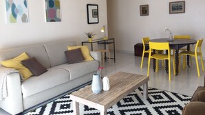 Una sala de estar con sofá, mesa de centro y comedor con sillas.