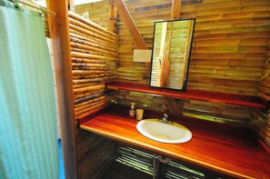 Un bagno rustico con parete in listelli di legno, un piano in legno, un lavandino e uno specchio.