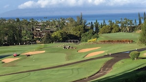 Ein Golfplatz mit Bunkern, einem Putting-Green und Blick auf das Meer.