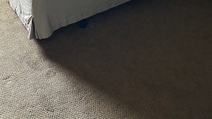 Ein ordentlich bezogenes Bett mit gemusterten Bettwäsche, einem dunklen Kopfteil und dekorativer Wandkunst.