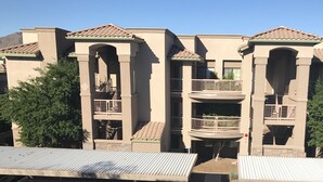 A multi-story building with a beige facade, multiple balconies, and a tiled roof. - PRIME LOCATION-GOLF, OLD TOWN, HIKE & BIKE, SPRING TRAINING, SHOPPING... (Scottsdale)