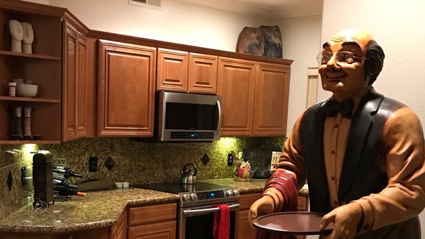A kitchen with wooden cabinets, a microwave, an oven, and a statue of a man holding a tray. - PRIME LOCATION-GOLF, OLD TOWN, HIKE & BIKE, SPRING TRAINING, SHOPPING... (Scottsdale)