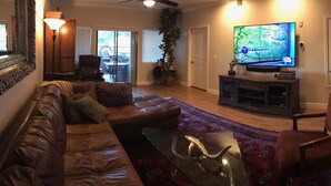 A living room with a leather sofa, a glass coffee table, a television, and a red patterned rug. - PRIME LOCATION-GOLF, OLD TOWN, HIKE & BIKE, SPRING TRAINING, SHOPPING... (Scottsdale)