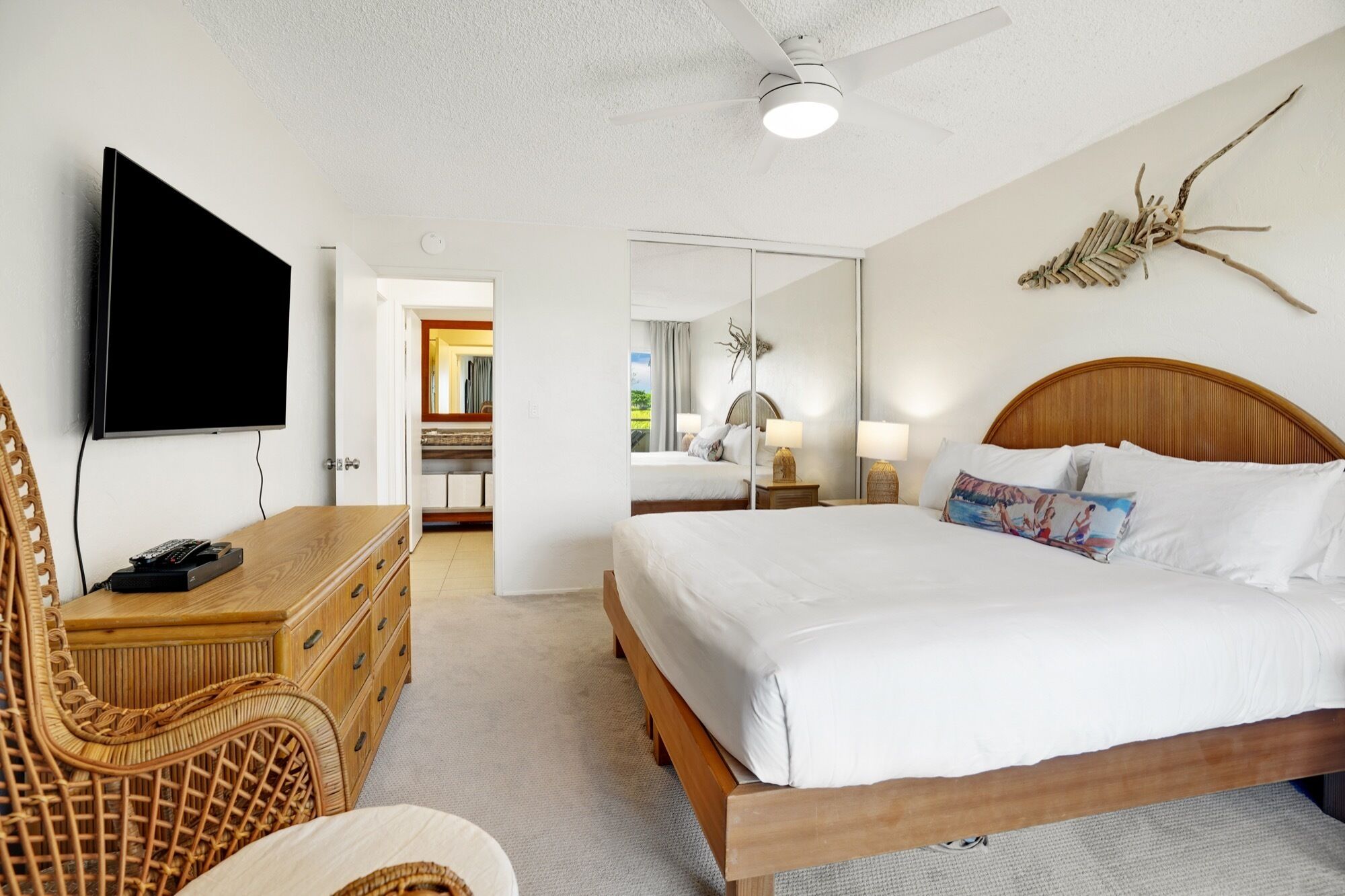 A hotel room with a bed, a television, a desk with a chair, and a wardrobe.