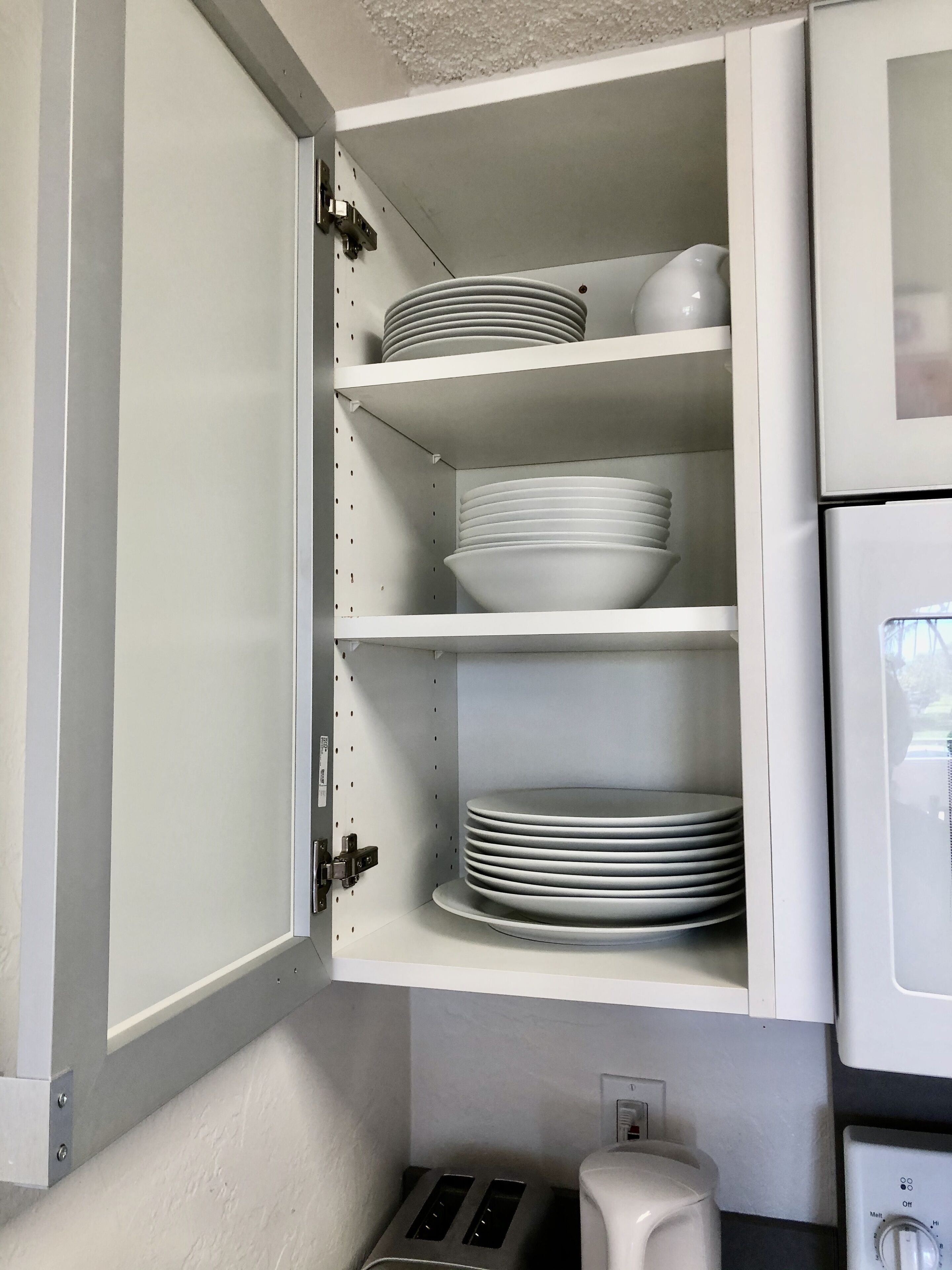 Een keuken met witte kastjes, een broodrooster en een koffiezetapparaat.
