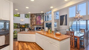 A spacious kitchen with a large island, white cabinetry, and a stone accent wall. -  Beautiful Lakefront Home with Pier and Buoy. (Glenbrook)