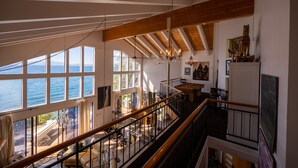 A spacious interior with high ceilings, large windows overlooking the sea, and a staircase connecting multiple levels. -  Beautiful Lakefront Home with Pier and Buoy. (Glenbrook)