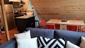 A cozy cabin interior with a dining area, kitchen, and a sofa with patterned cushions. - A-Frame Cabin Escape in George Washington Natl Forest, Lost River Area, WV (Wardensville)