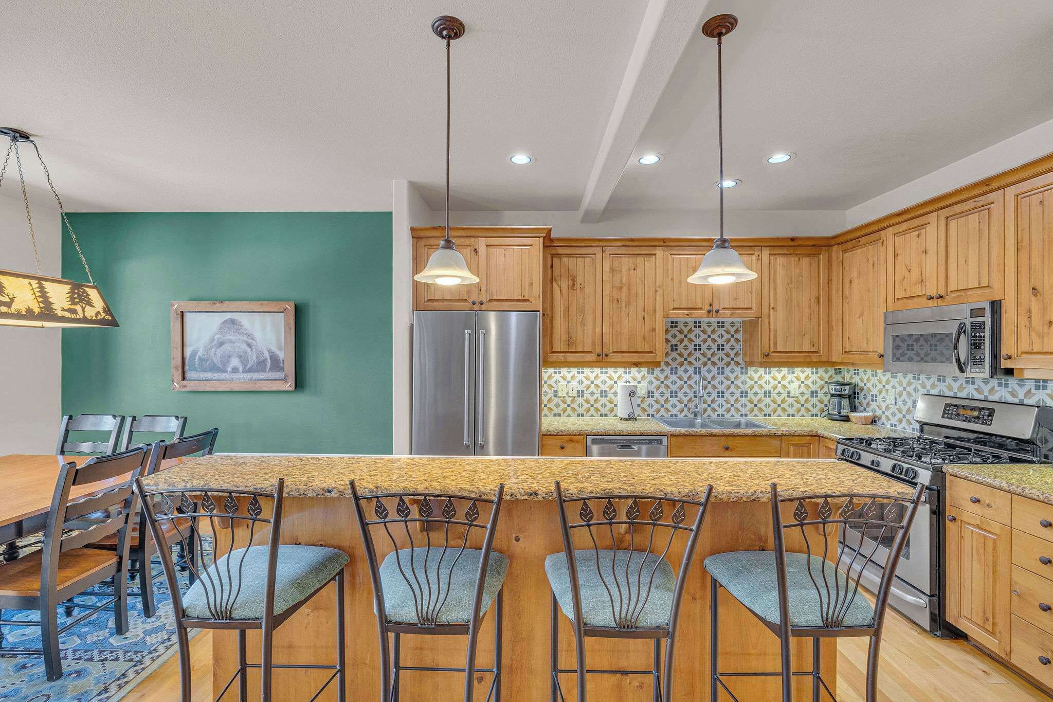 A kitchen with wooden cabinets, stainless steel appliances, a granite countertop, and pendant lighting.
