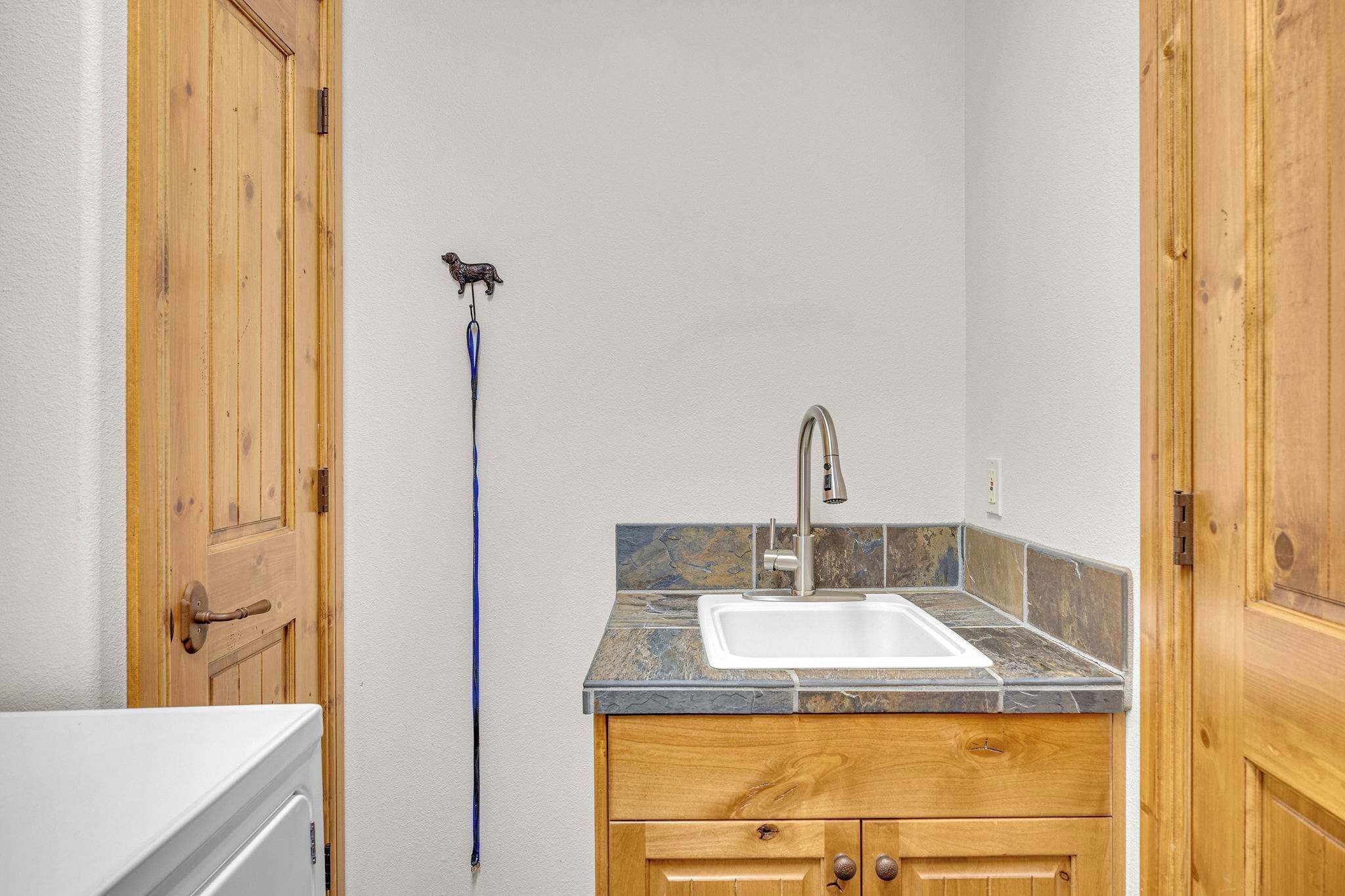 A small kitchen with a sink, wooden cabinets, and a door with a handle.