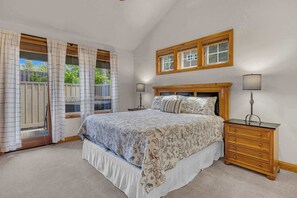 Een slaapkamer met een bed, twee nachtkastjes, een raam met gordijnen en een houten hoofdbord.